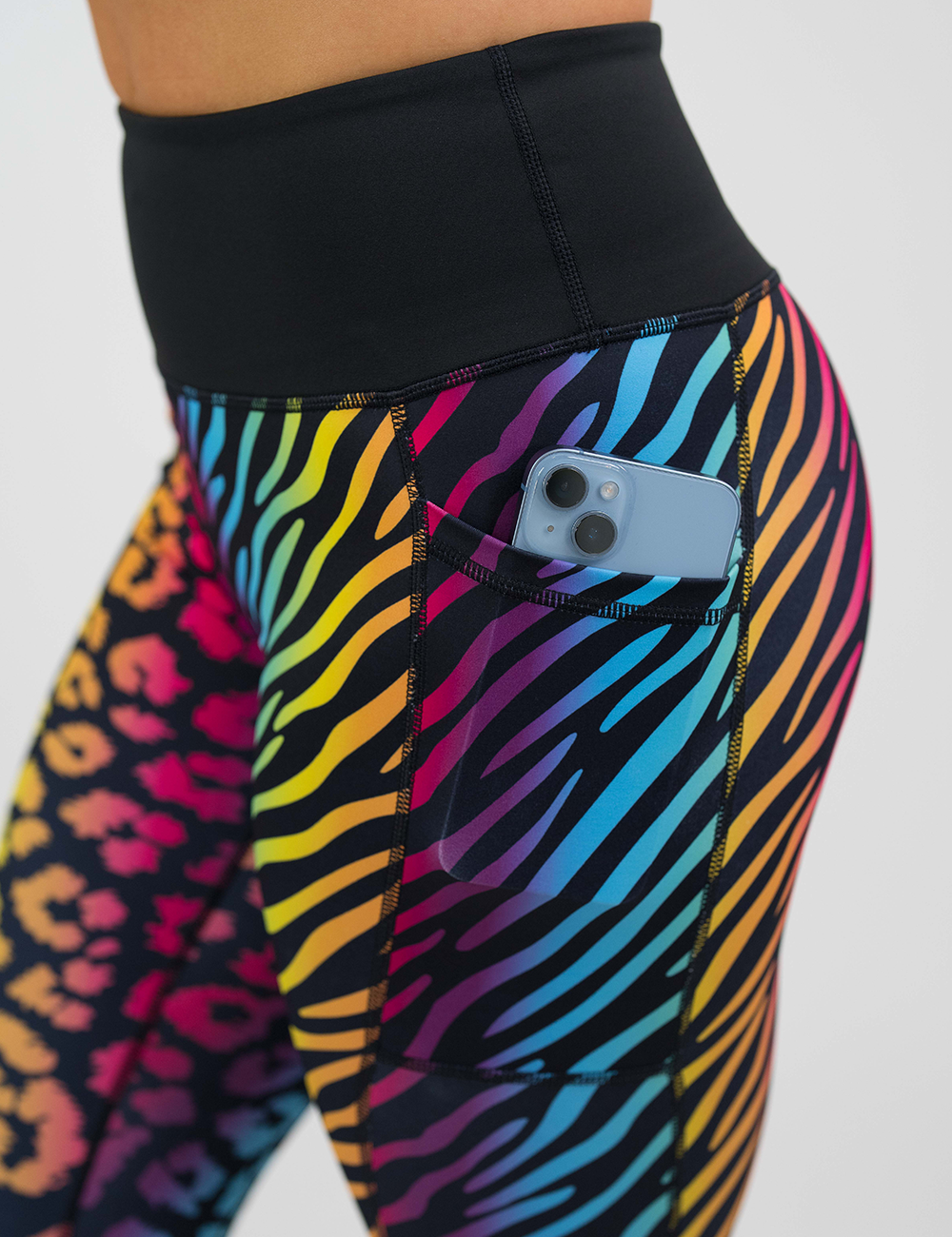 close up of the rainbow leopard and zebra print leggings showing a phone in the pocket against a white background