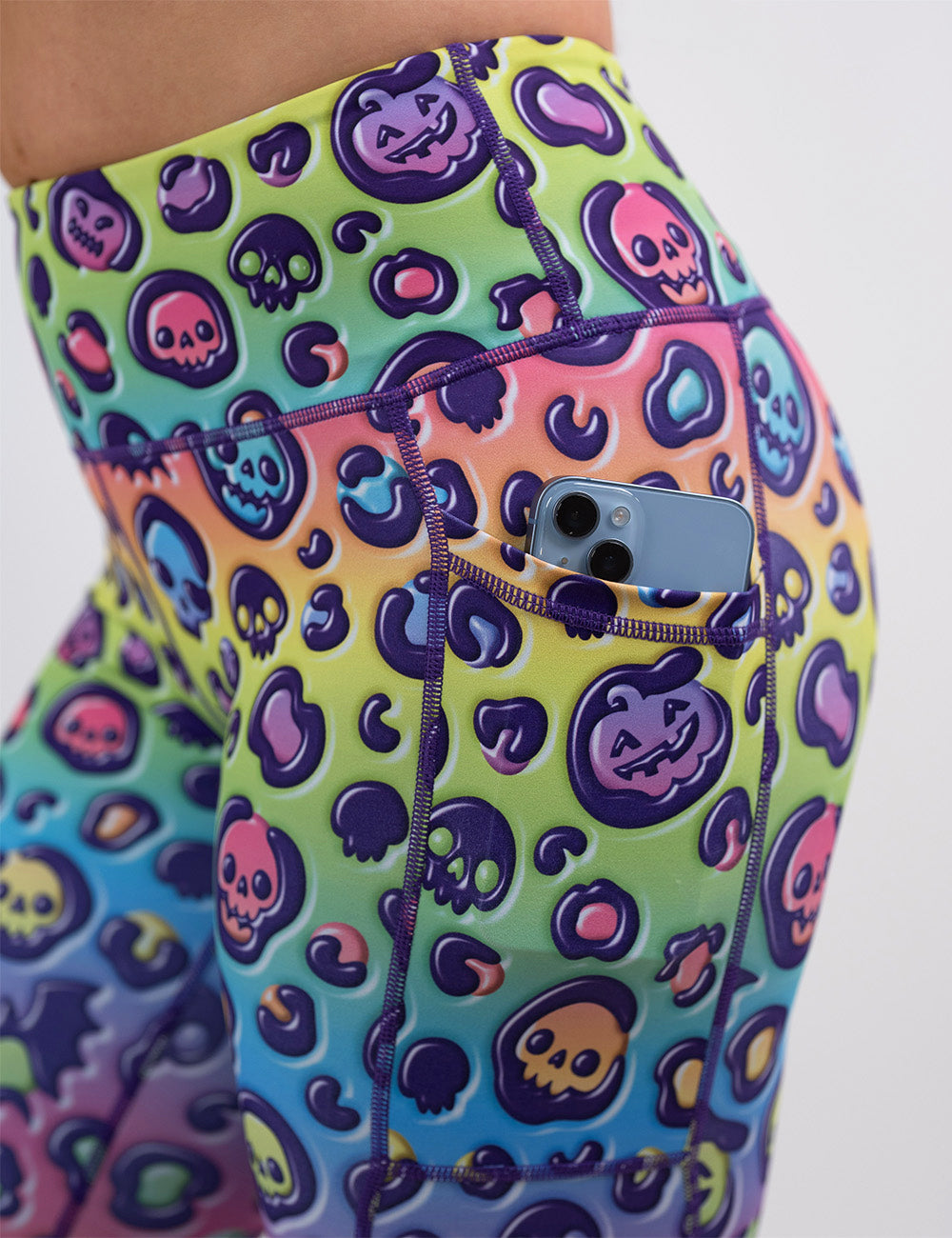 close up of the rainbow leopard print pumpkins and skulls leggings with a phone in its pocket