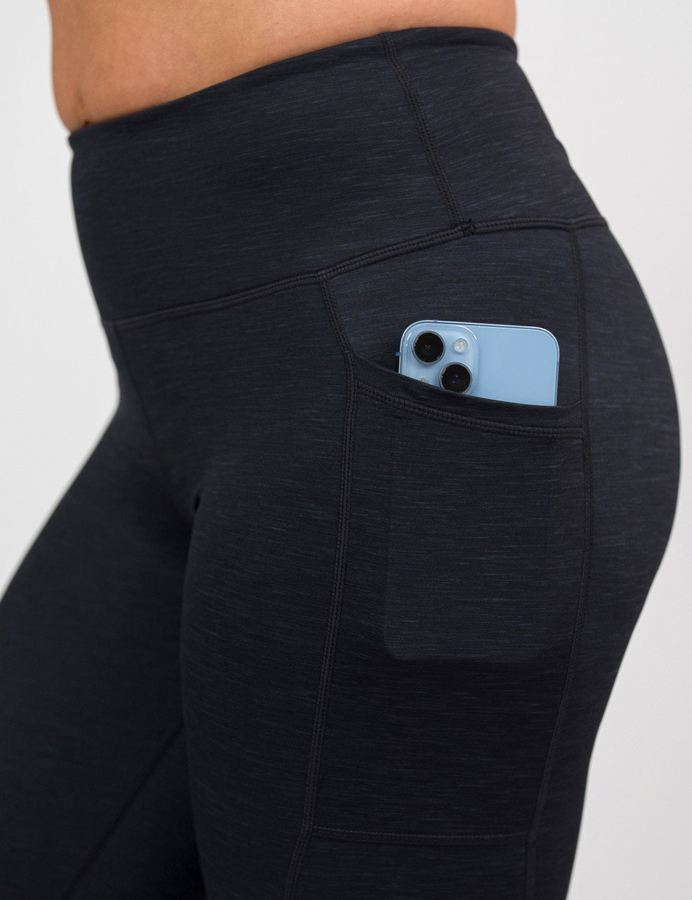 close up of the black heather pattern leggings with a phone in its pocket