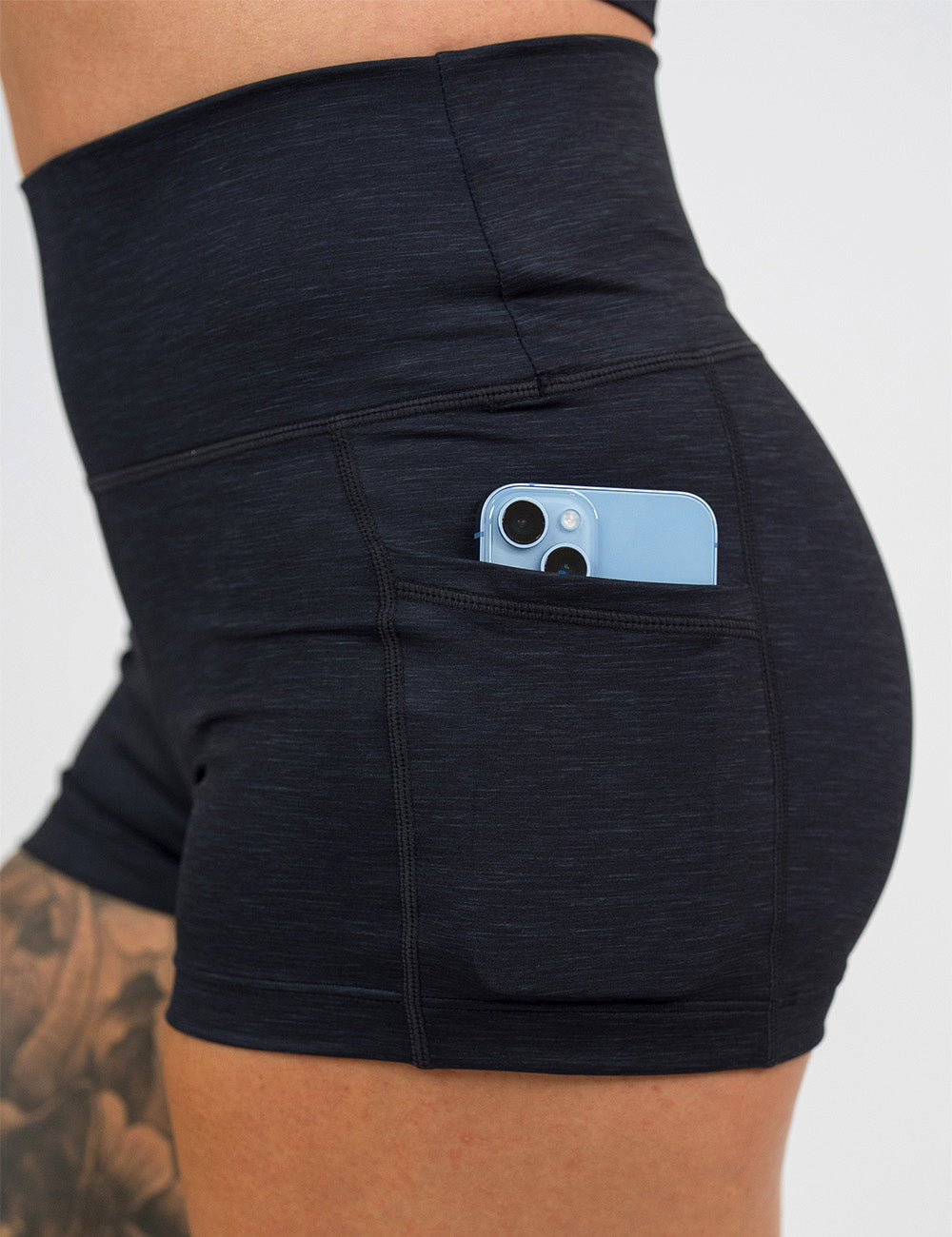 close up of the 2.5 inch black heather pattern shorts with a phone in its pockets