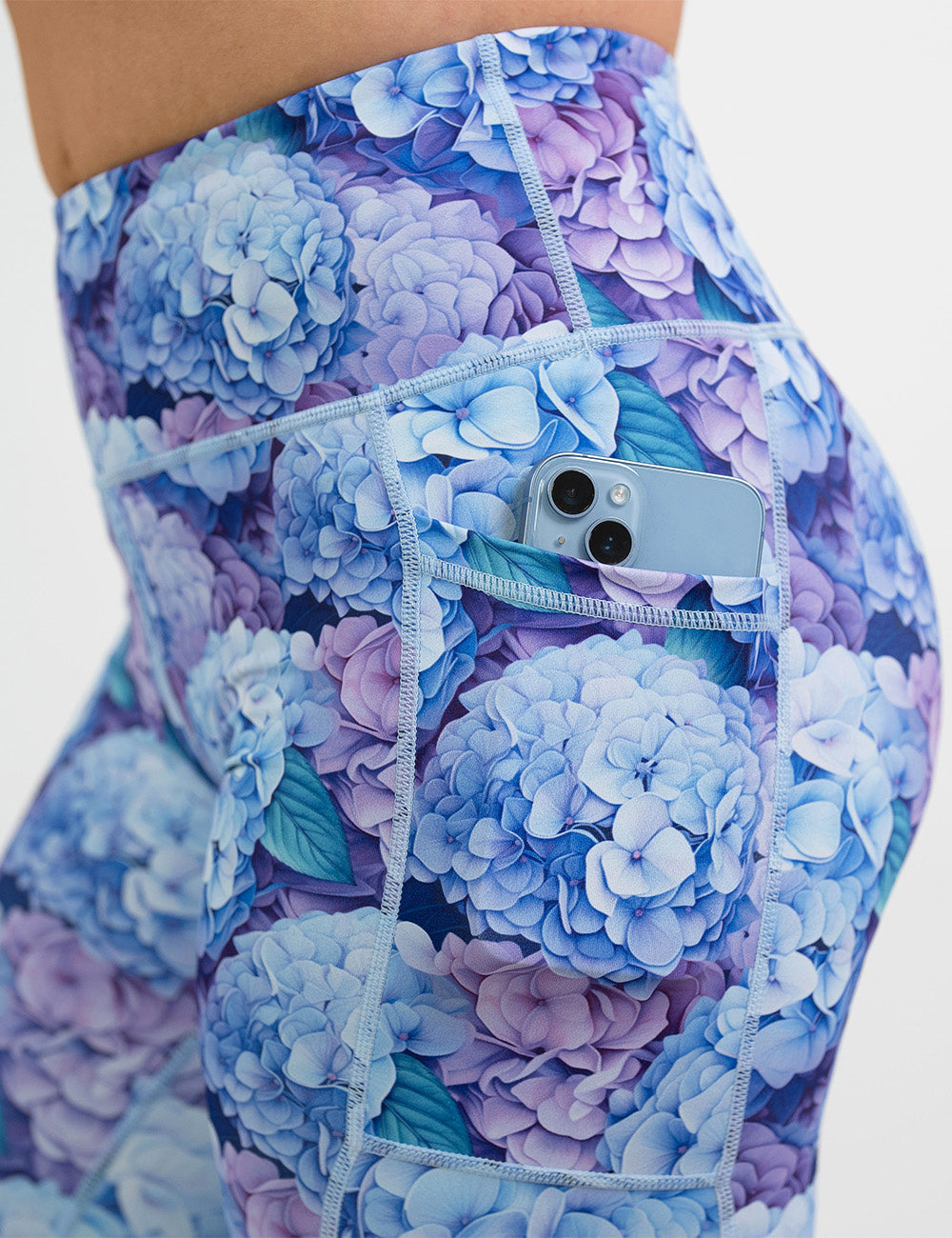 close up of the pastel blue and purple hydrangea flower pattern leggings with a phone in its pocket