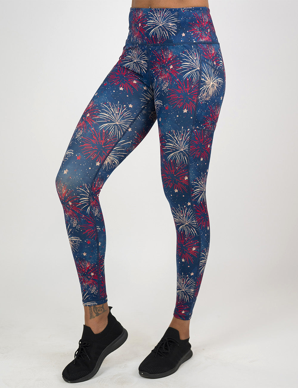 front of the full length blue leggings with a red and white fireworks pattern against a white background