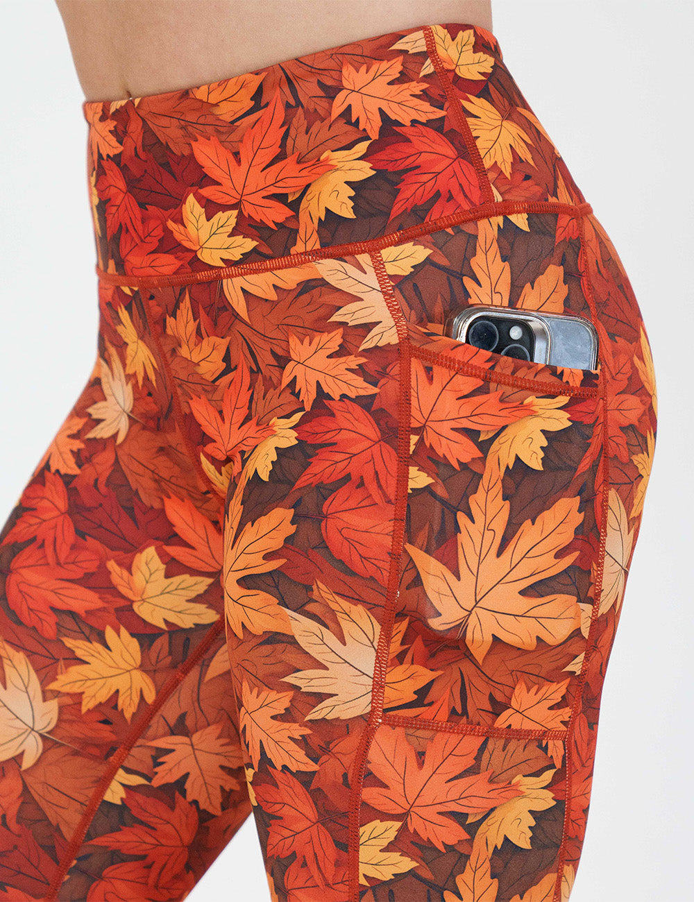 close up of the orange leaves leggings with a phone in its pocket
