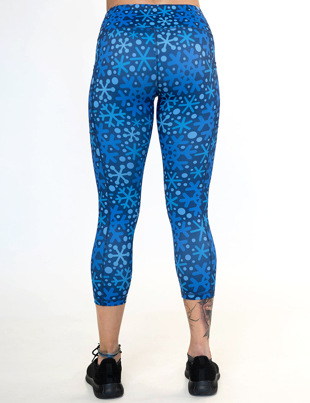 back of the blue snowflakes on a dark blue background capri leggings against a white background