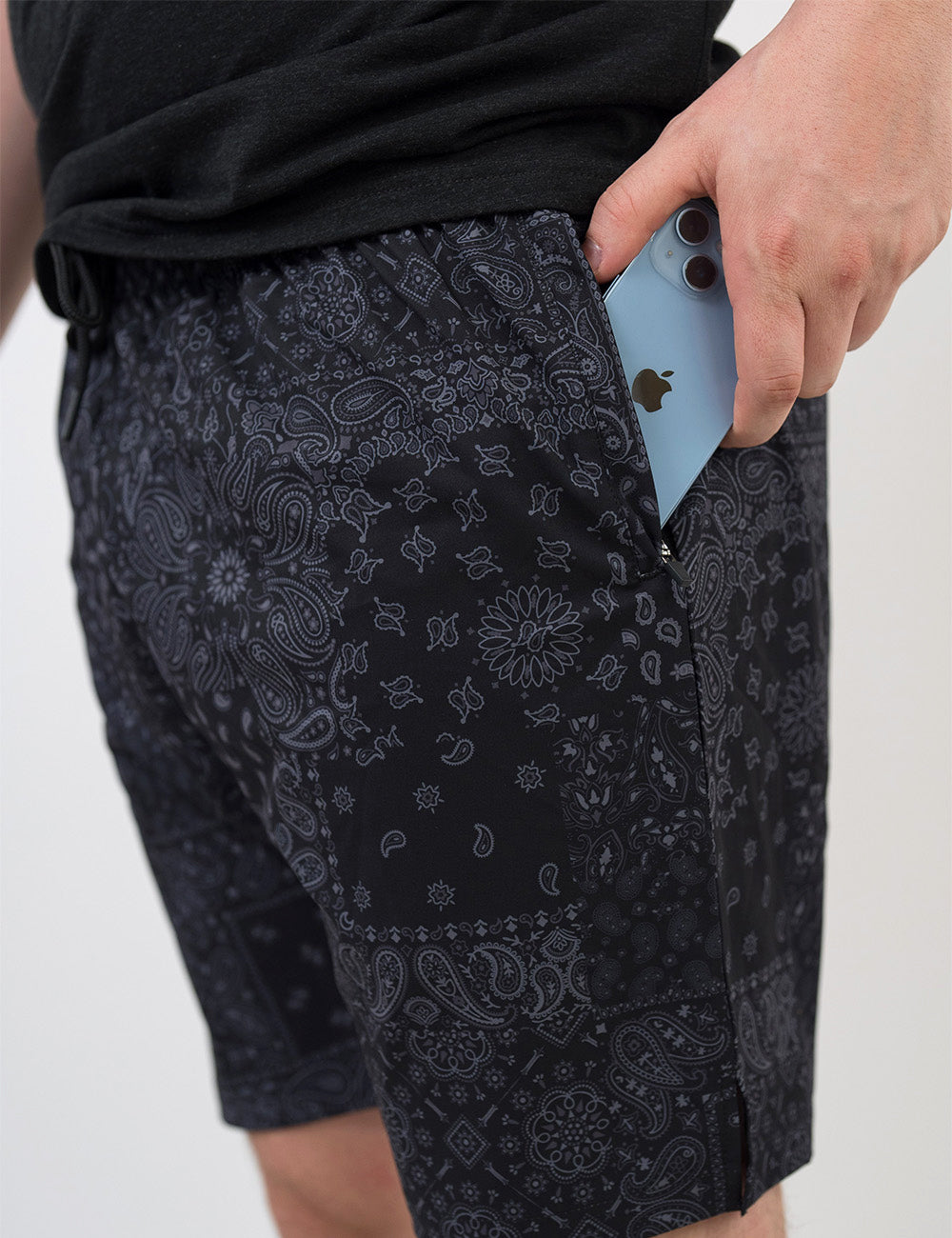 close up of the black men's shorts with a grey paisley pattern holding a phone in its pocket against a white background