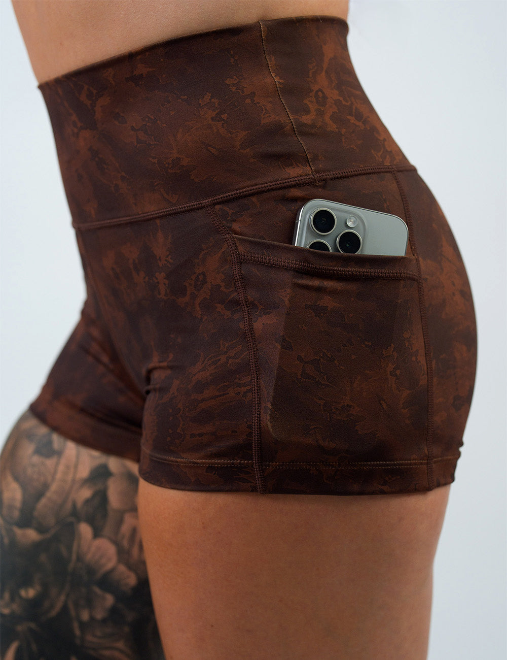 close up of the brown tie dye 2.5 inch shorts with a phone in its pocket