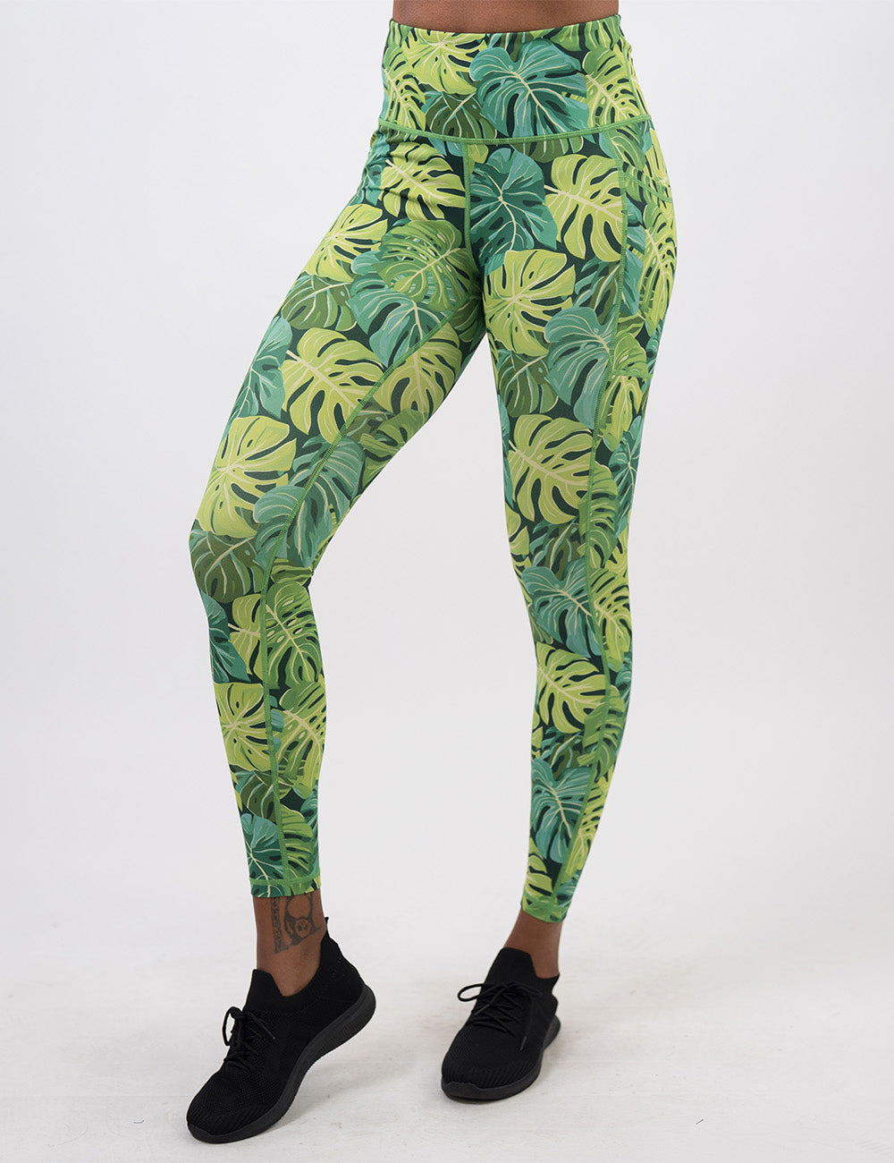 front of the full length green tropical leaves leggings against a white background