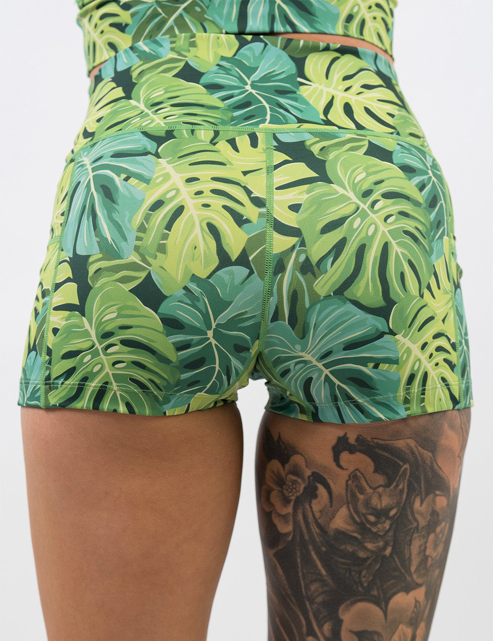 back of the 2.5 inch green tropical leaves shorts against a white background