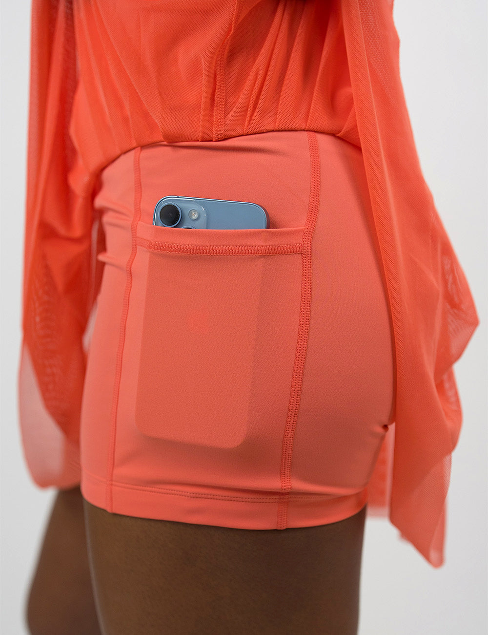 close up of the shorts underneath the sheer orange skirt holding a phone