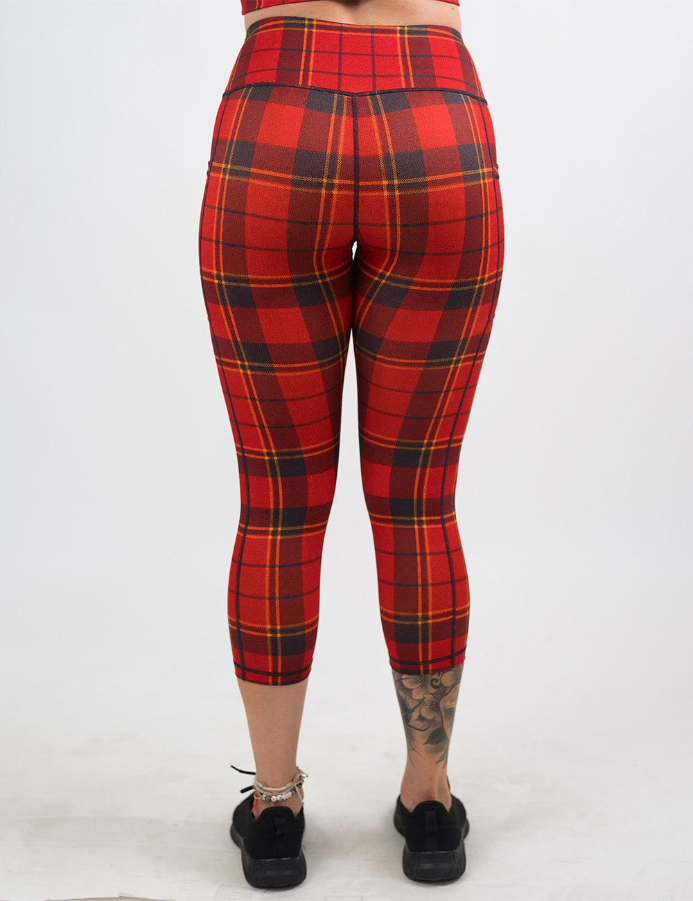 back of the capri red, yellow, and dark grey plaid leggings against a white background