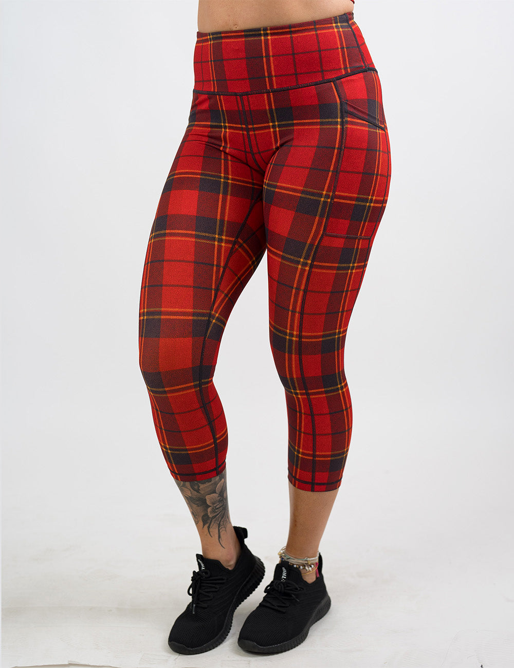 front of the red, yellow, and dark grey plaid capri leggings against a white background