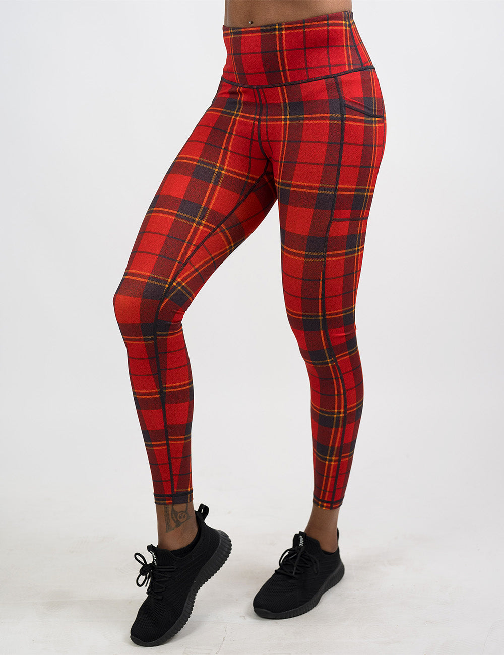 front of the full length red, yellow, and dark grey plaid leggings against a white background