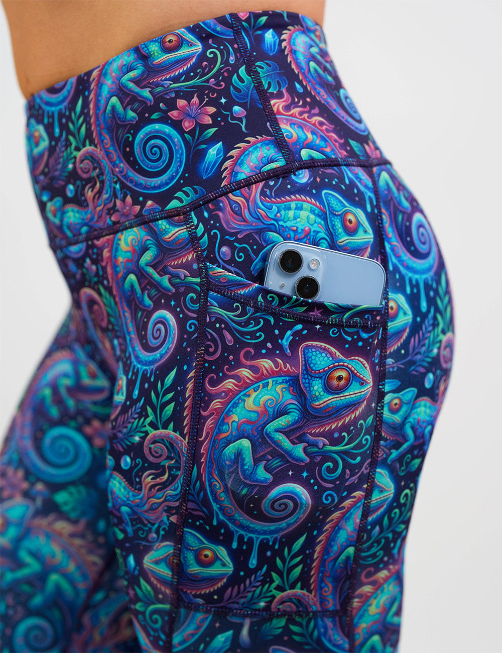 close up of the orange, blue, and red chameleons surrounded by plants leggings with a phone in its pocket