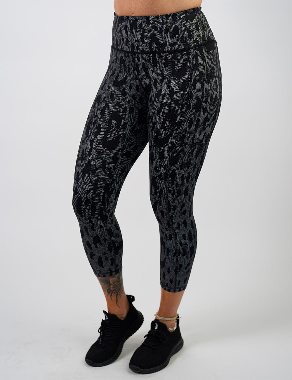 front of the dark spots surrounded by a reflective background capri leggings against a white background