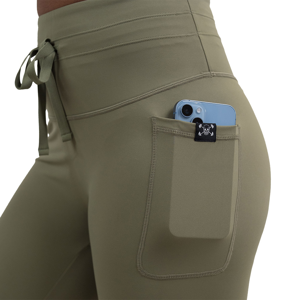 close up of the omni green tea leggings with a phone in the pocket against a white background