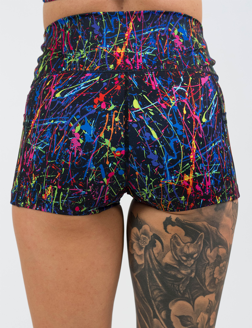 back of the rainbow paint splatter against a black background 2.5 inch shorts against a white background