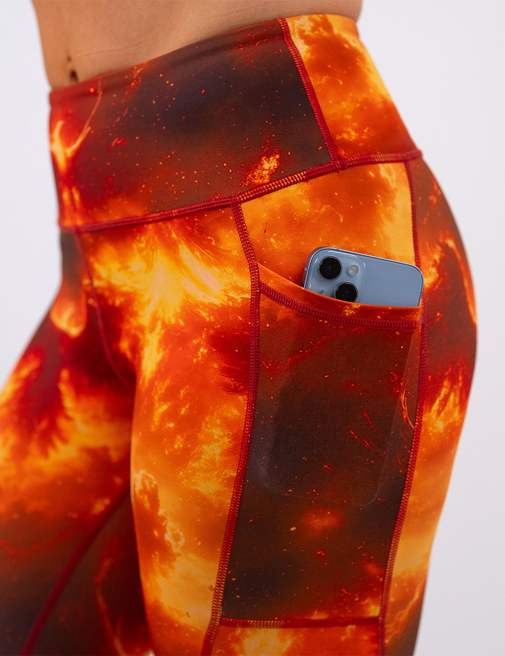 close up of the phoenix surrounded by fire leggings with a phone in its pocket