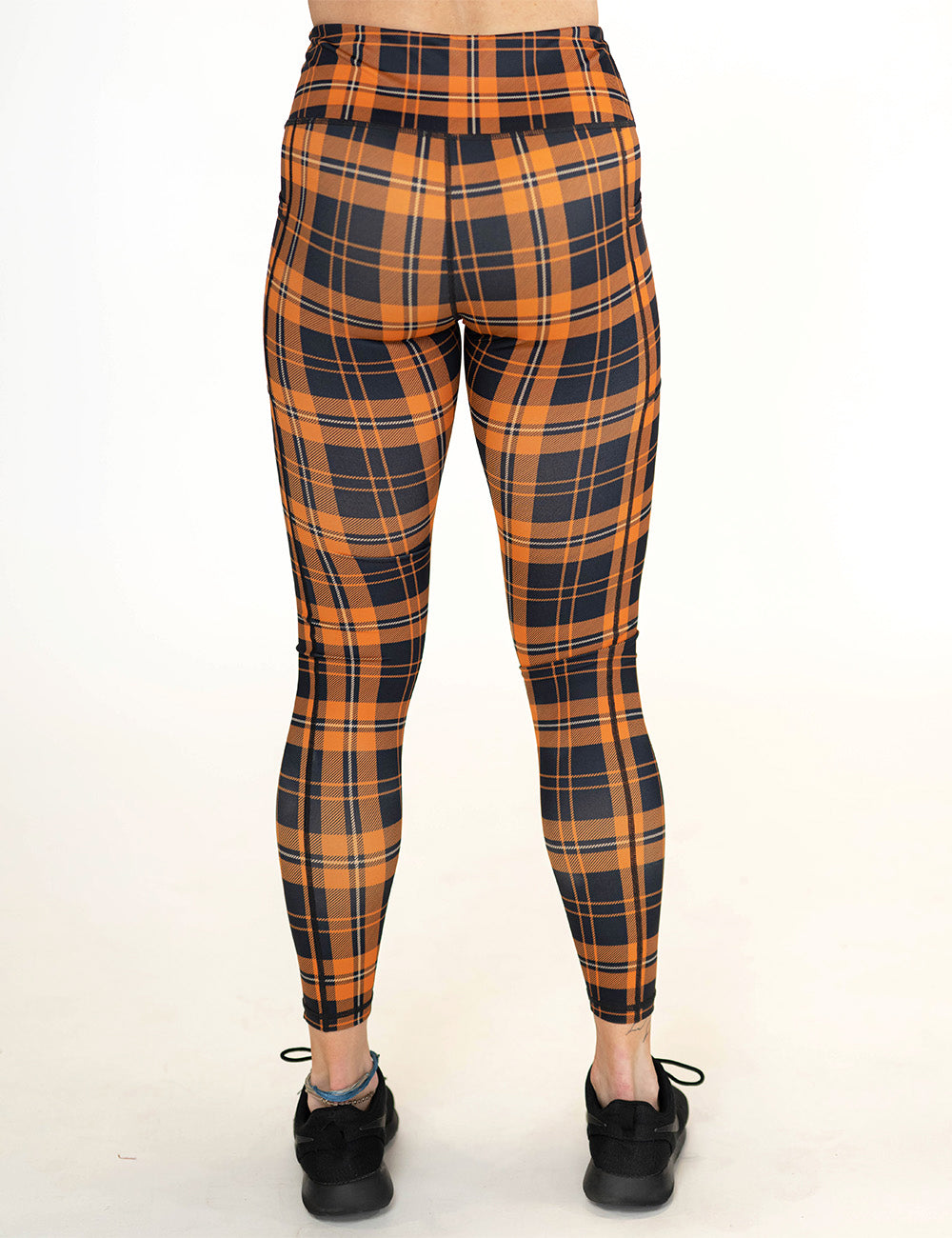 back of the full length black and orange plaid leggings against a white background