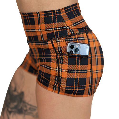 Orange and black plaid shorts with a phone in the pocket on a white background