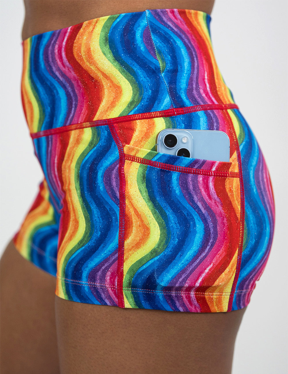 close up of the 2.5 inch rainbow waves shorts with a phone in its pocket against a white background