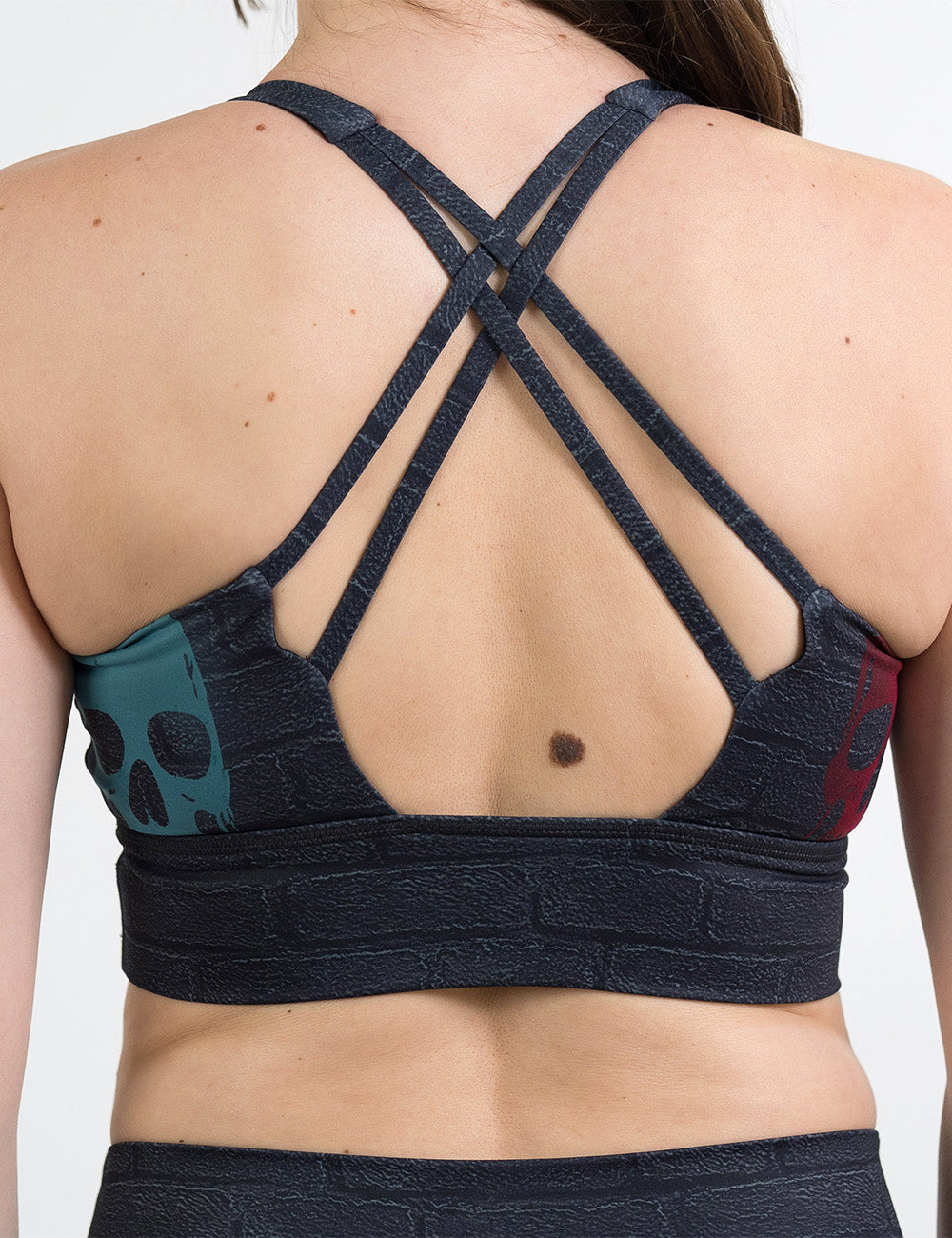 back of the black brick style longline bra with yellow, teal, and red skulls spray painted all over
