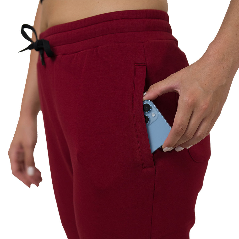 Person wearing dark red sweatpants with a pocket, holding a blue phone.