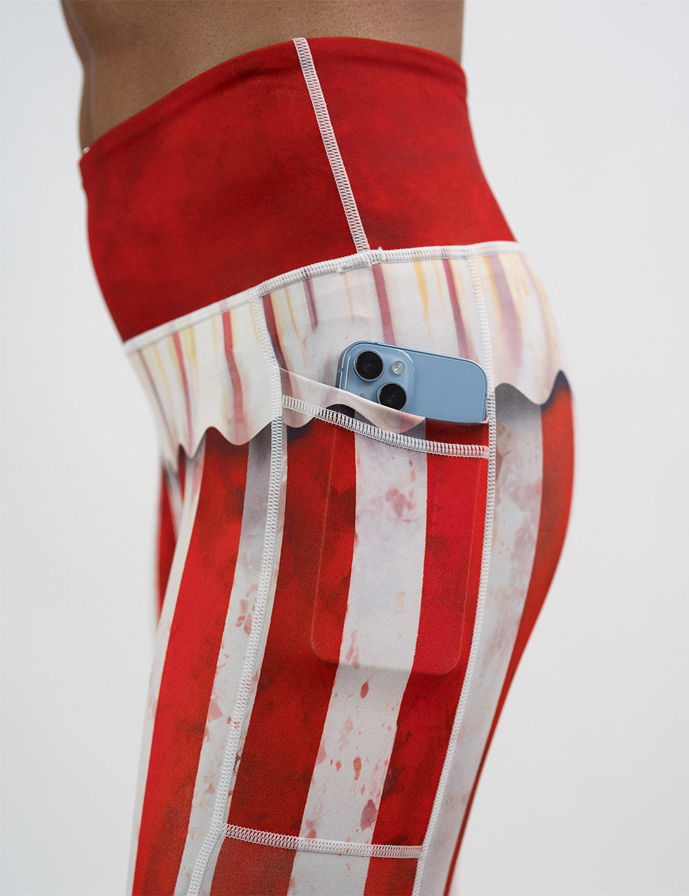 close up of the bloody red and white stripes circus leggings with a phone in its pocket