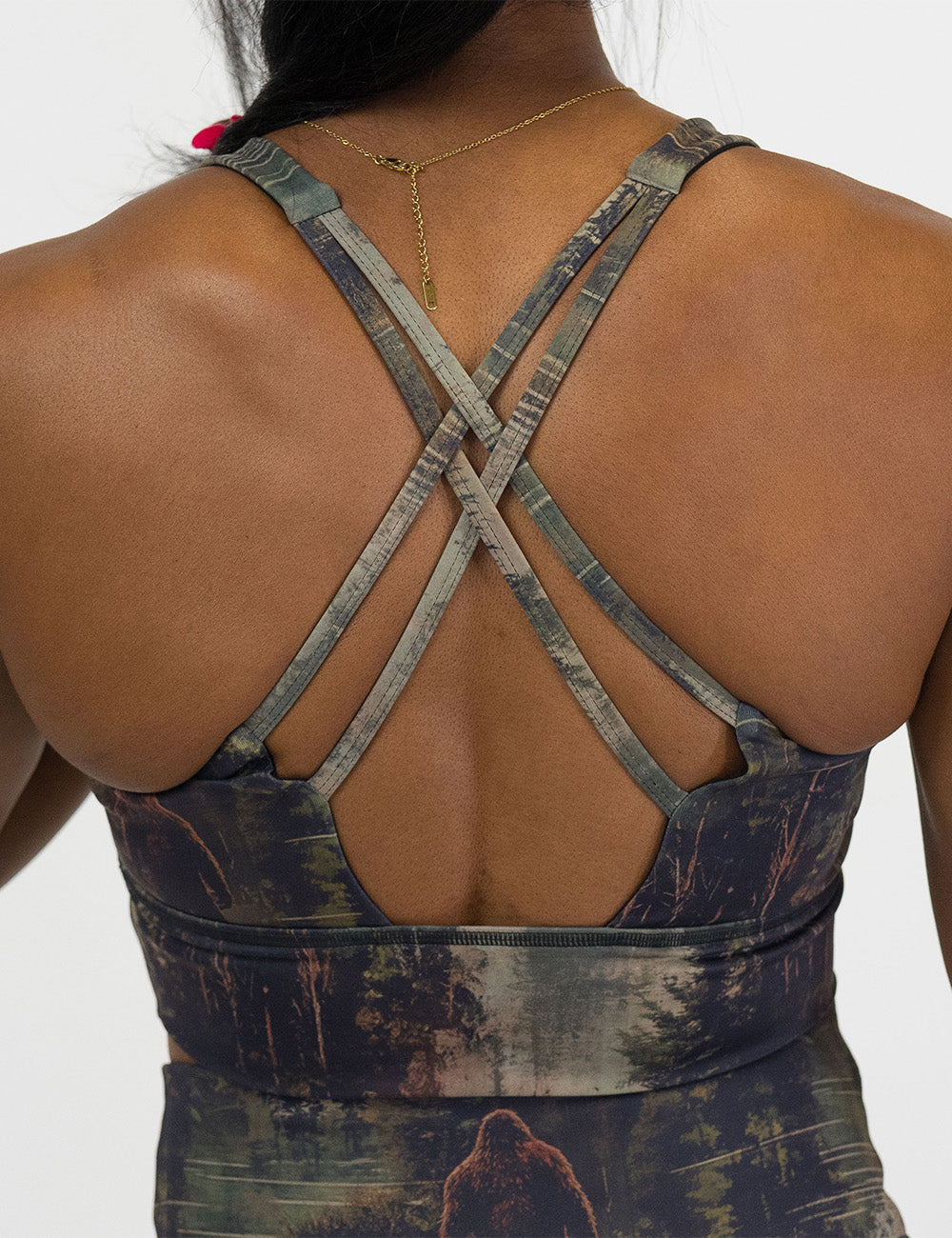 back of the bigfoot in a forest sports bra against a white background