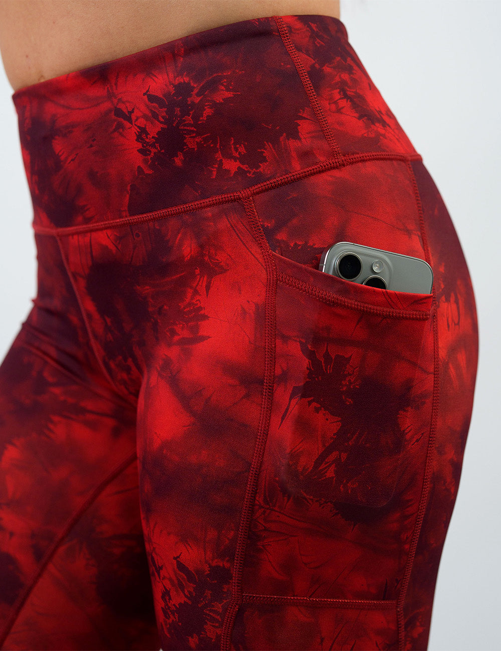 close up of the dark red tie dye leggings with a phone in it pocket against a white background