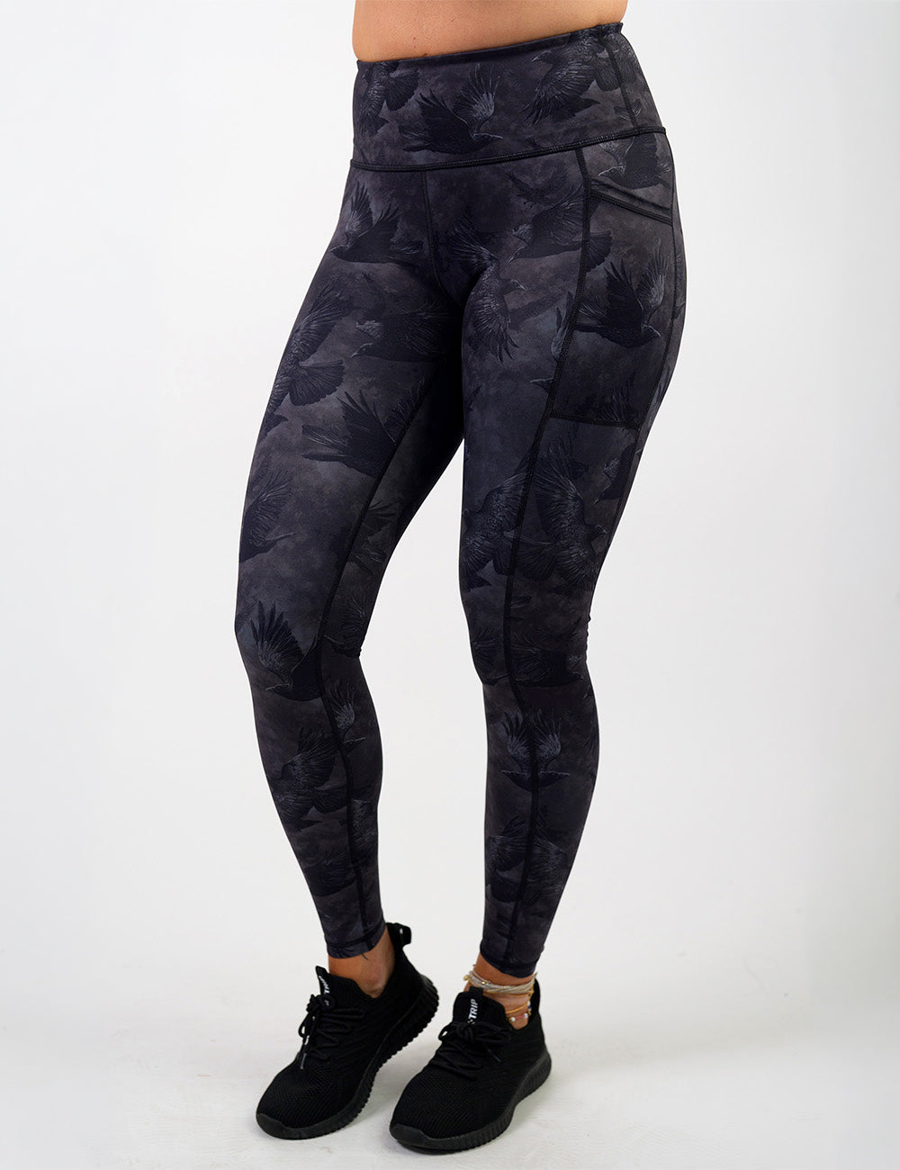 front of the dark ravens against a smokey grey and black background full length leggings against a white background