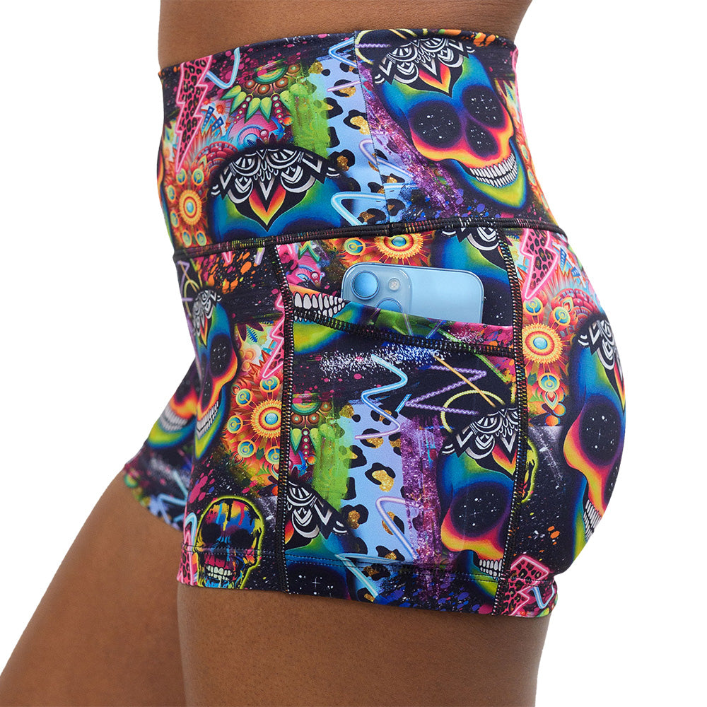 close up of the the brightly colored psychedelic skulls pattern against a busy background full of designs 2.5 inch shorts with a phone in the pocket against a white background
