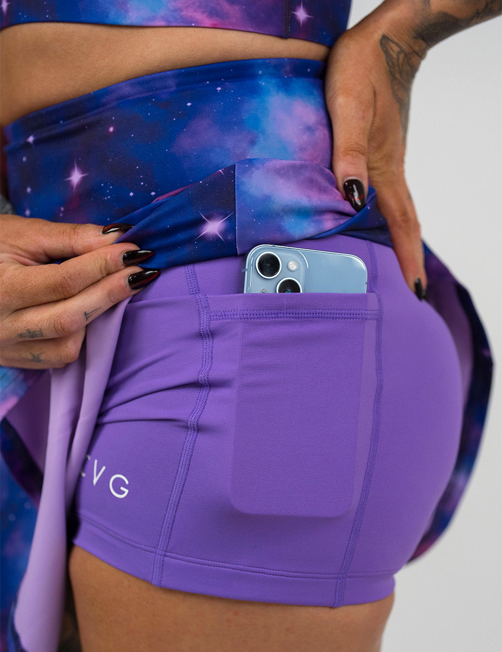 close up of the purple and blue space skirt pulled up to show the shorts lining underneath with a phone in the pocket