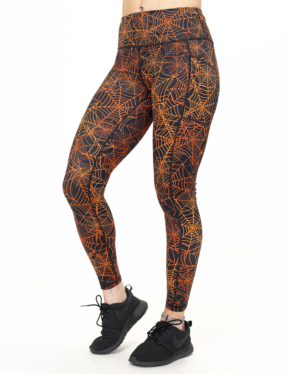 front of the orange spider webs against a black background full length leggings against a white background