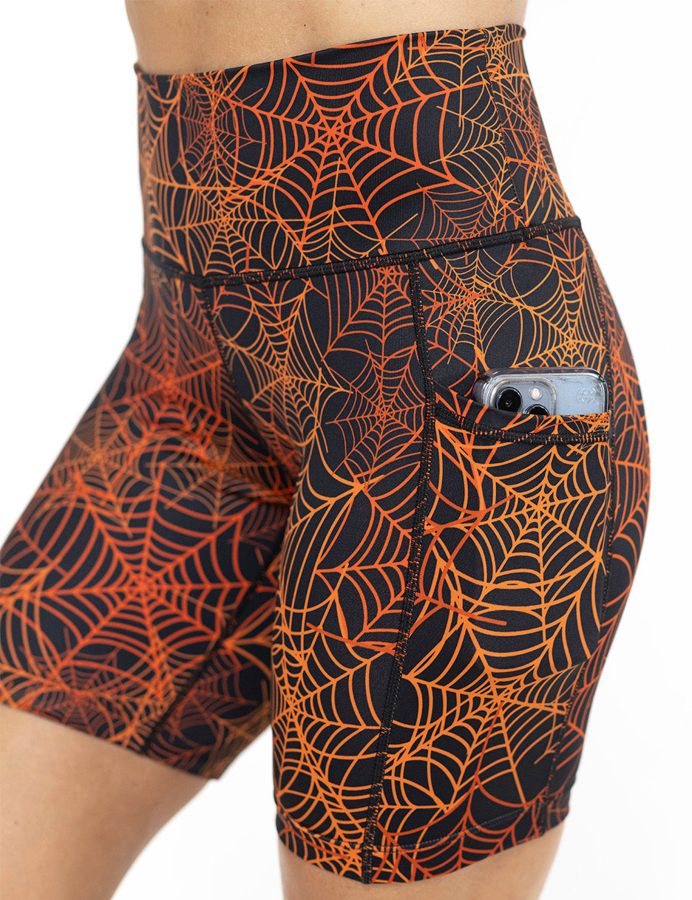 close up of the 5 inch orange spider webs against a black background shorts with a phone in its pocket