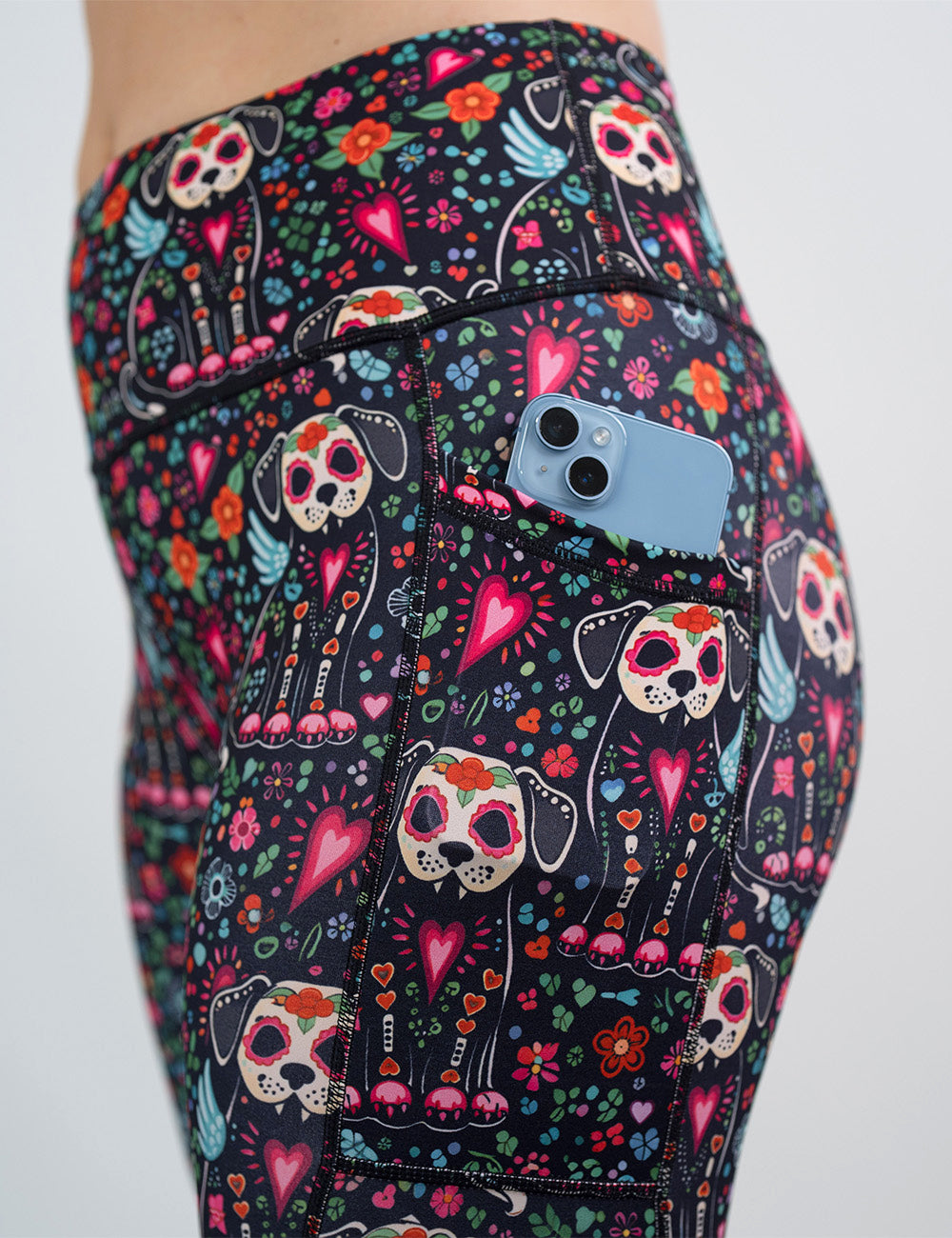 close up of the skeleton dogs surrounded by flowers legging with a phone in its pocket