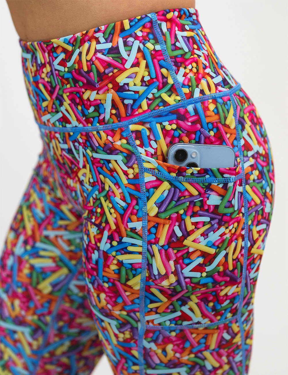 close up of the rainbow sprinkles leggings with a phone in the pocket against a white background