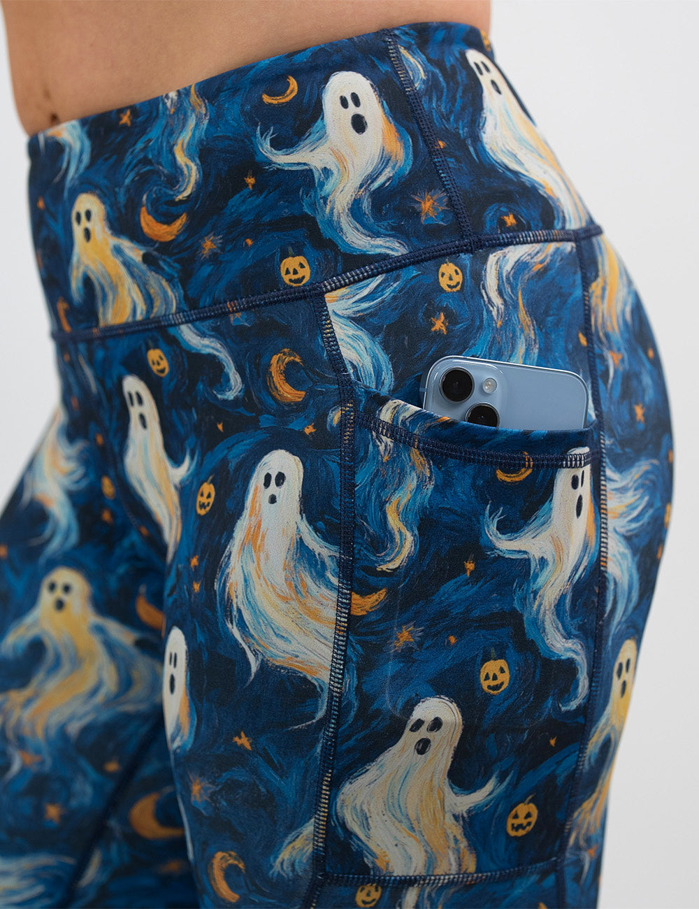 close up of the starry night ghosts against a blue background pattern leggings with a phone in its pocket