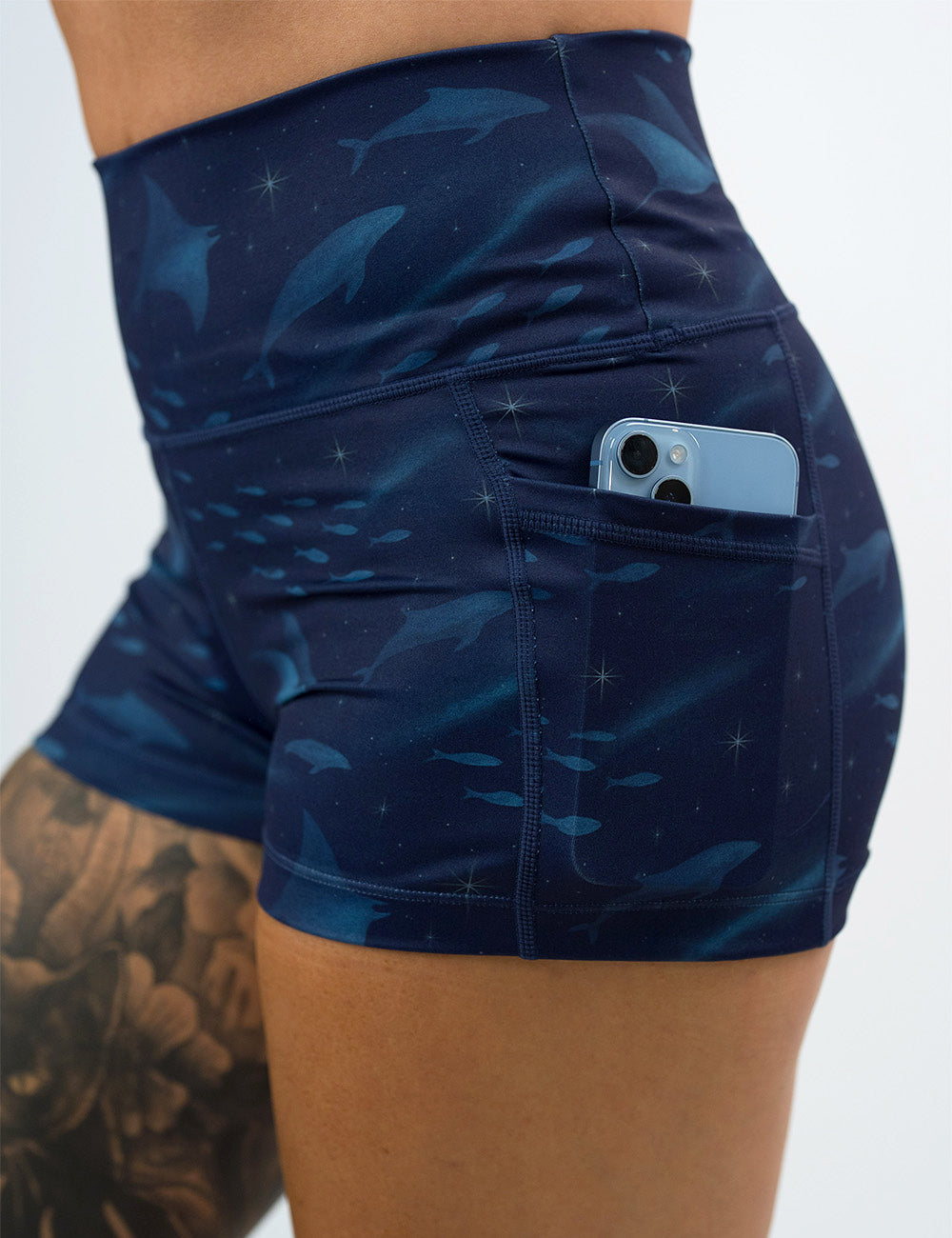close up of the 2.5 inch dark blue ocean filled with sting rays, whales, and fish shorts with a phone in the pocket