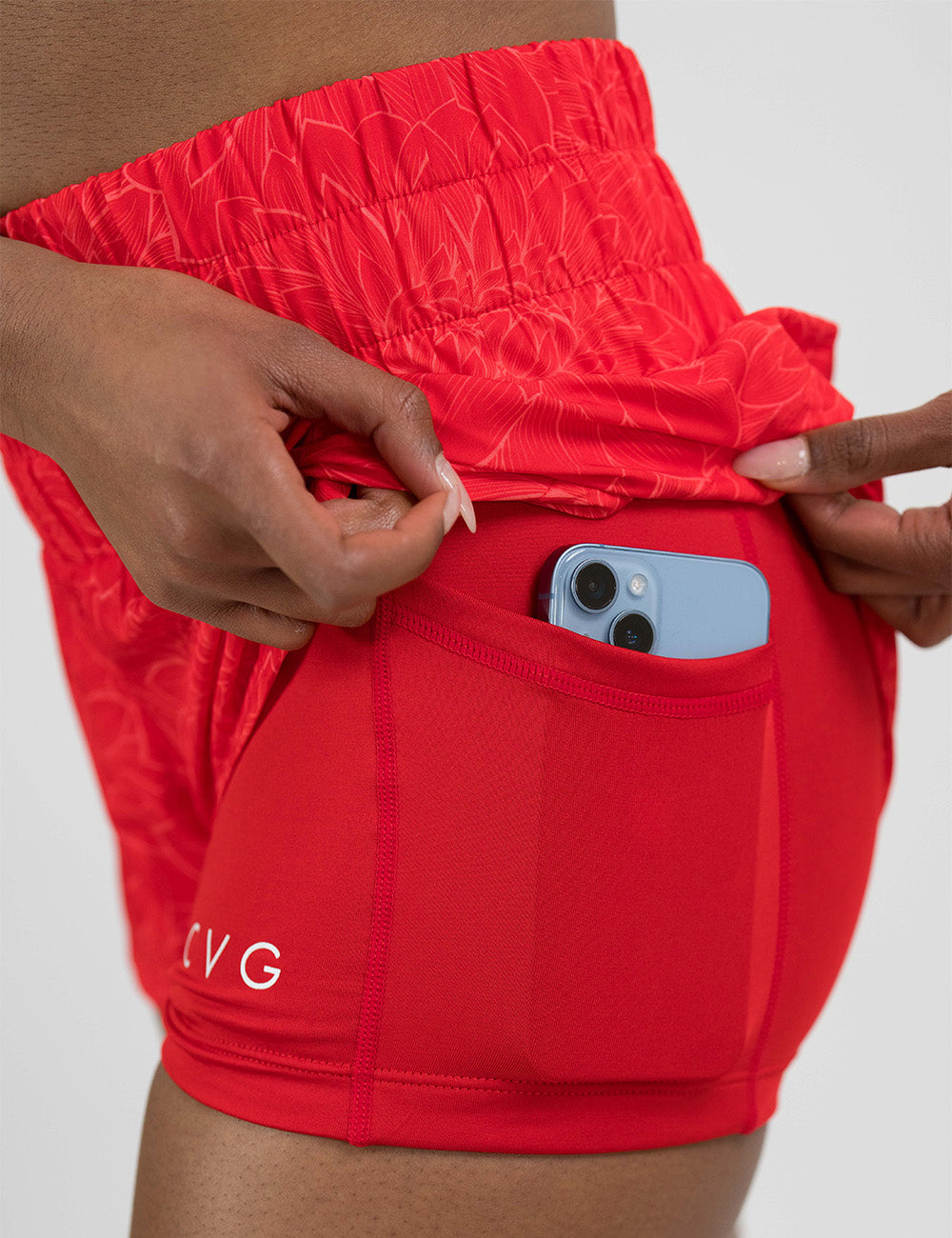 orange lotus day dream shorts pulled up to show the pocket underneath holding a phone