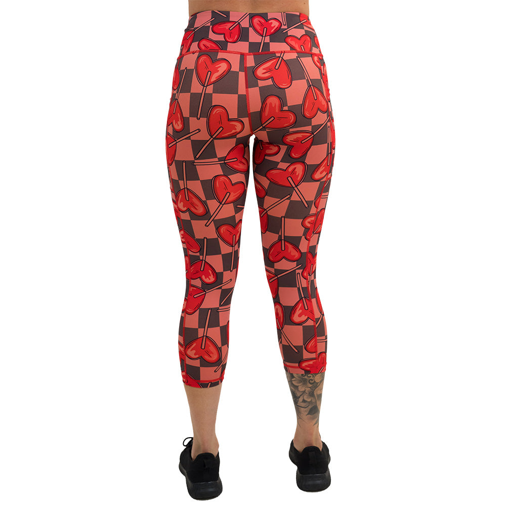 back of the heart lollypops on a checker board background pattern capri leggings against a white background
