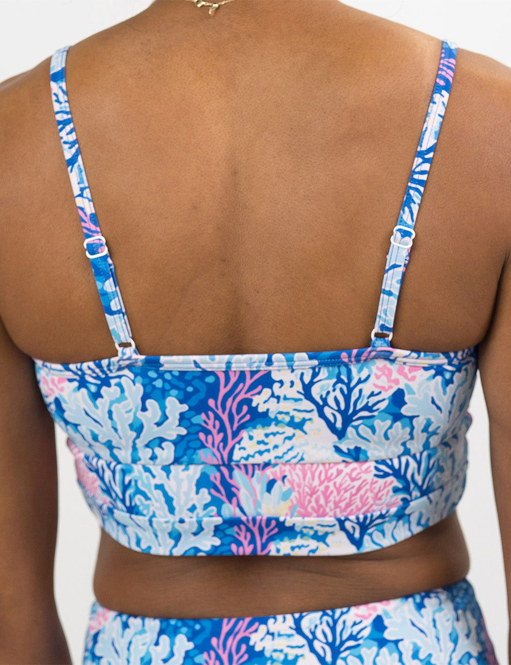 back of the pink and blue coral swimsuit top against a white background