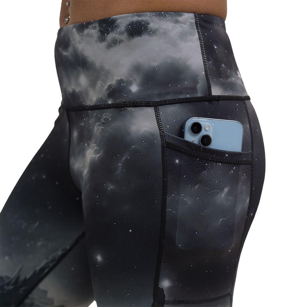 close up of the black leggings with mountain and star pattern with a phone in the pocket against a white background
