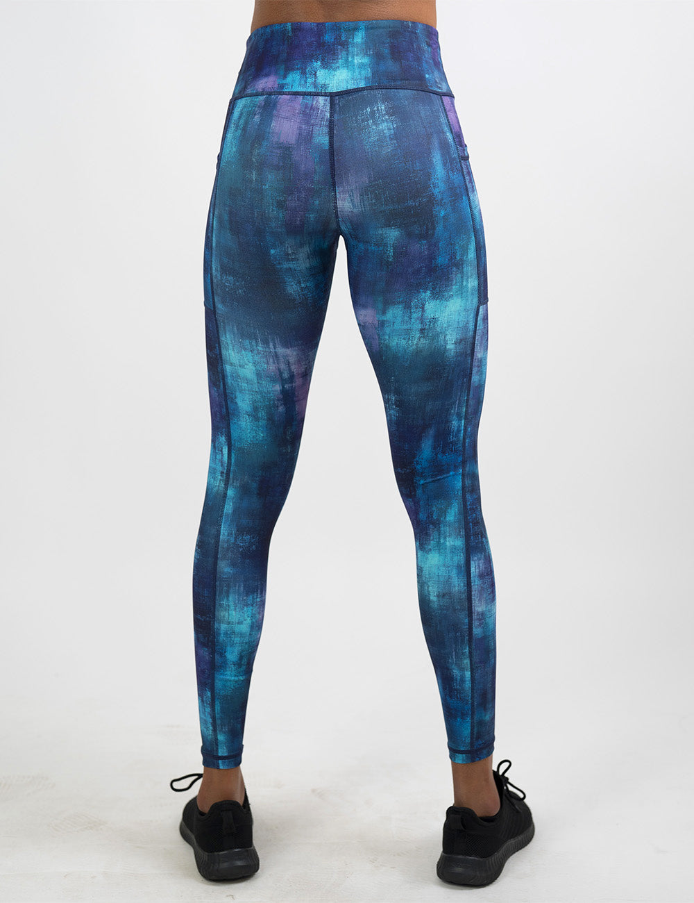 back of the full length blue, teal, and purple grunge concrete pattern leggings against a white background