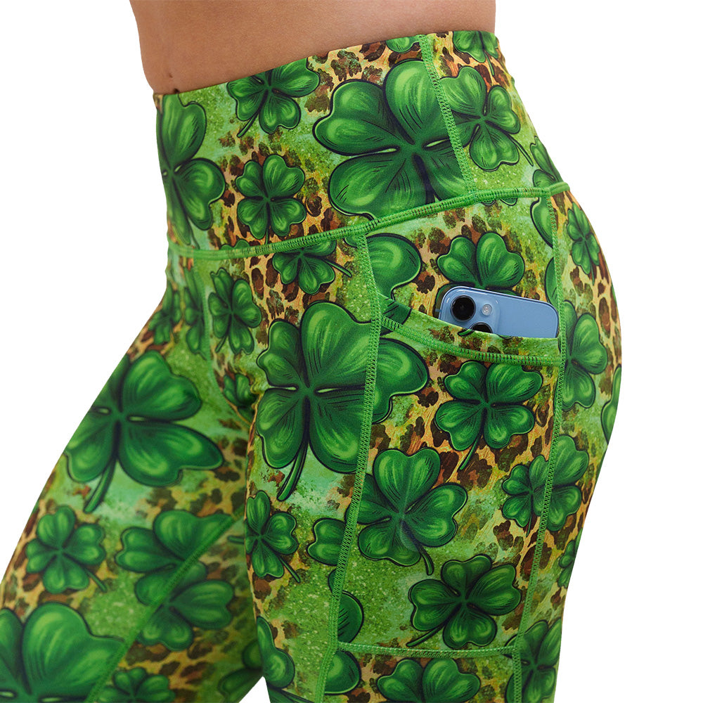 close up of the clover pattern against a cheetah print and green background leggings with a phone in the pocket