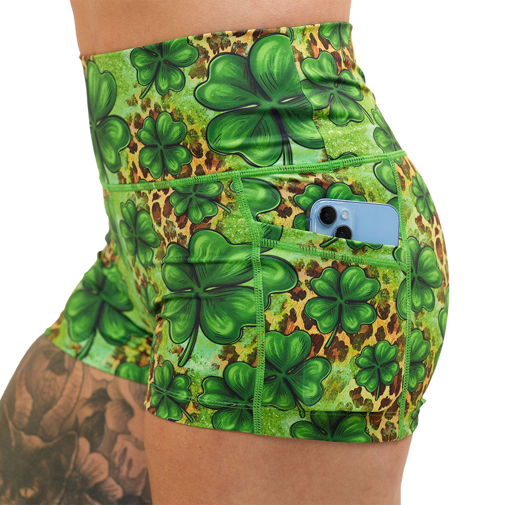 close up of the clover pattern against a cheetah print and green background 2.5 inch shorts with a phone in the pocket