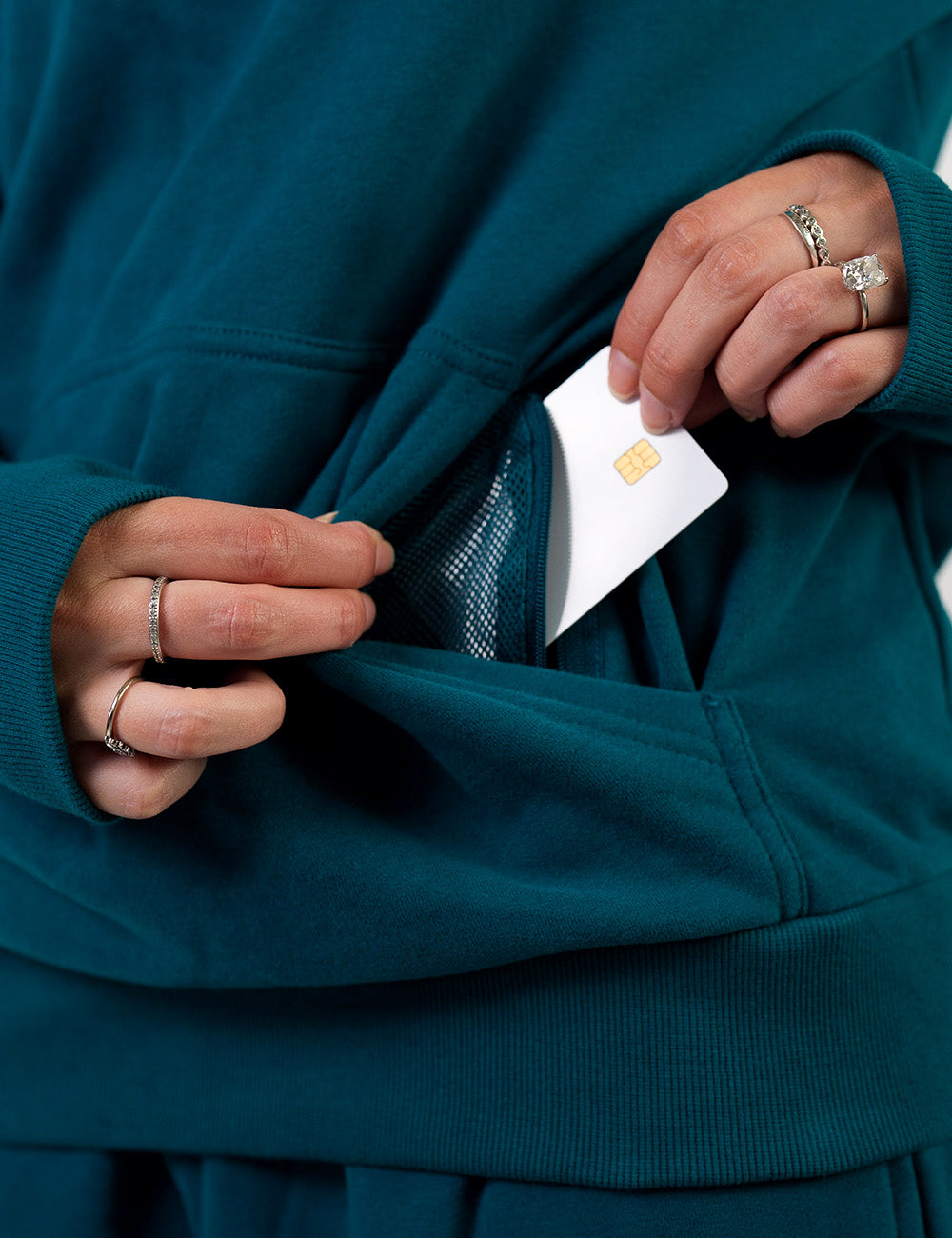 close up of the dark blue hoodie's mesh lined zipper pocket holding a credit card