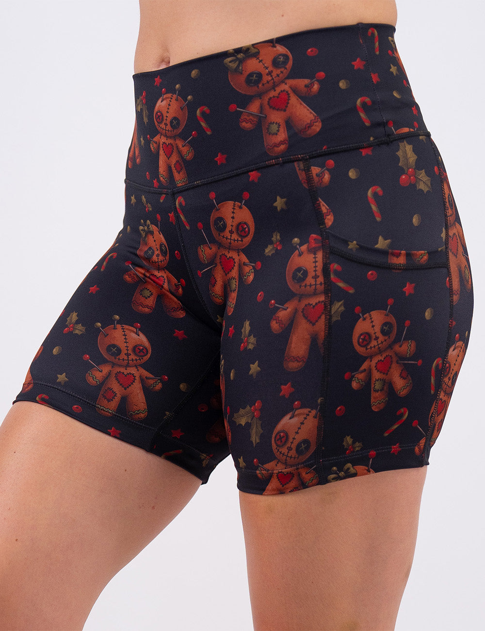 front of the gingerbread voodoo dolls with pins in them surrounded by berries and stars on a black background 5 inch shorts 