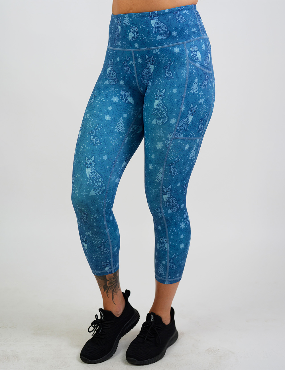 front of the blue foxes, owls, and bunnies in a winter landscape capri leggings against a white background