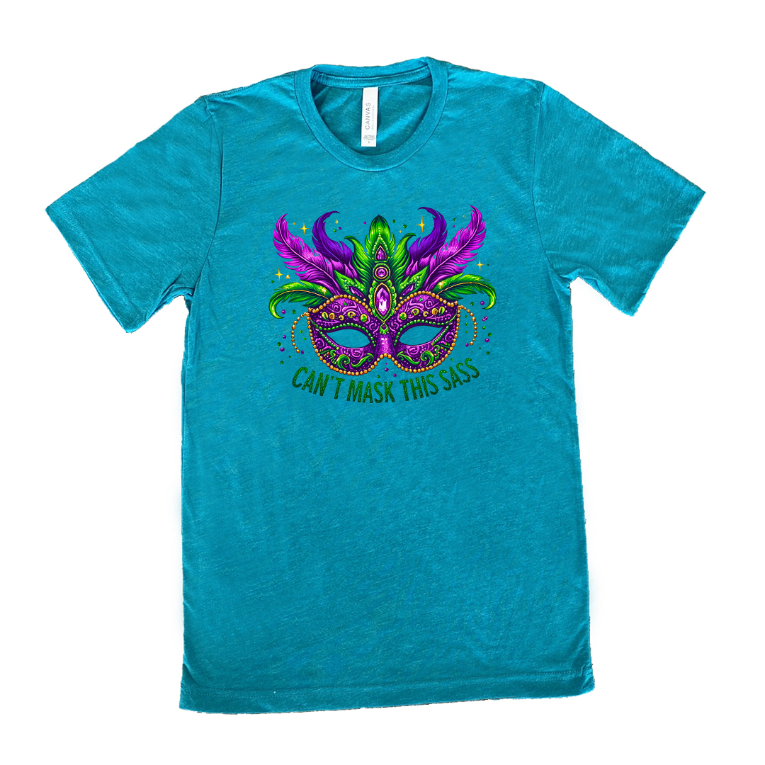 teal unisex tee with the graphic of a fancy, feathered and bejeweled, and colorful mardi gras mask, and words underneath saying "can't mask this sass"