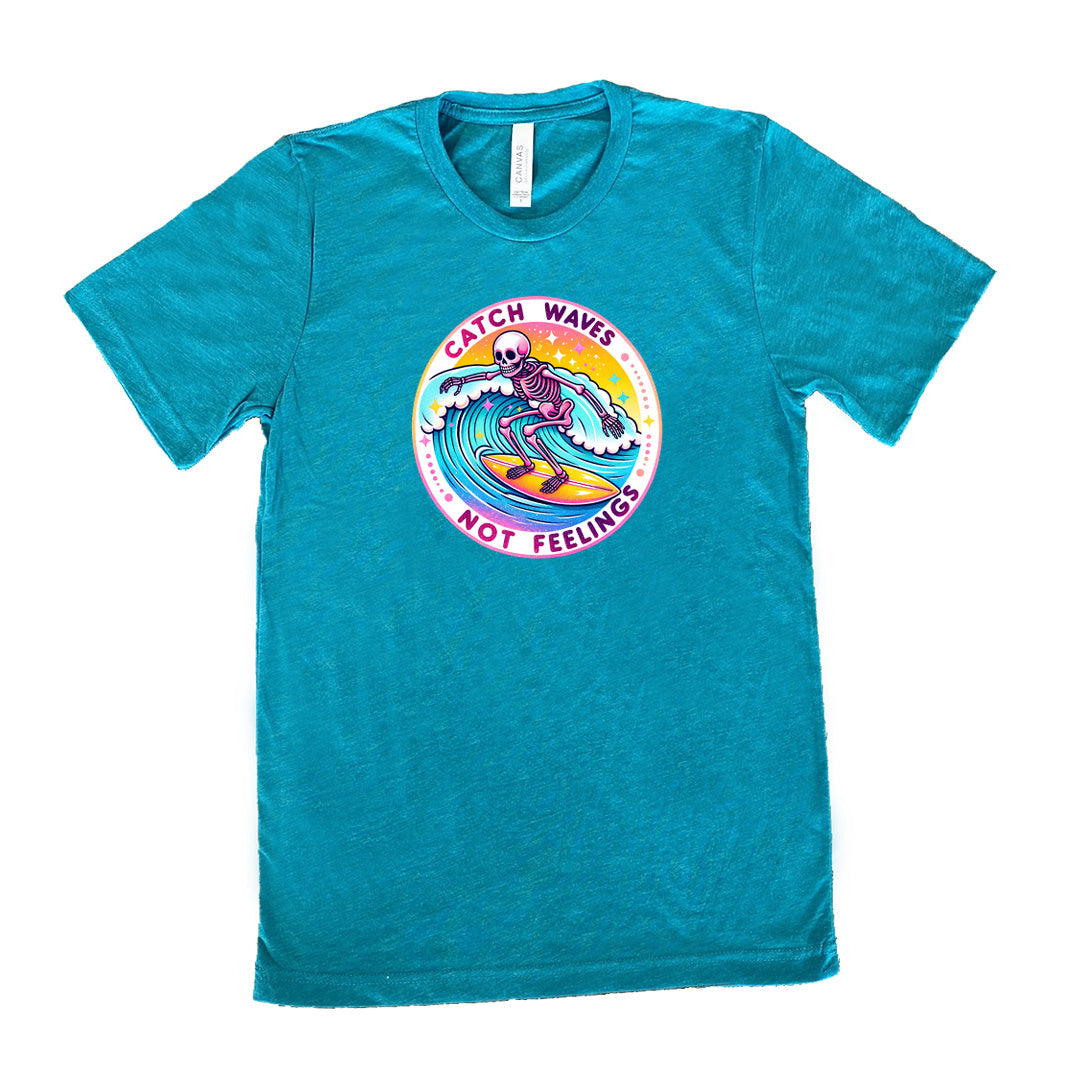 Teal colored shirt with a skeleton surfing graphic on it that says "Catch Waves Not Feelings" 